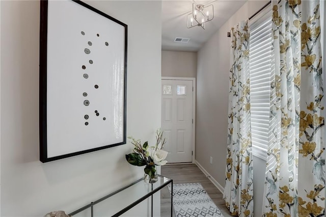 doorway to outside featuring a notable chandelier and light wood-type flooring