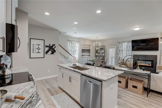 kitchen featuring sink, white cabinetry, a kitchen island with sink, stainless steel appliances, and light stone counters