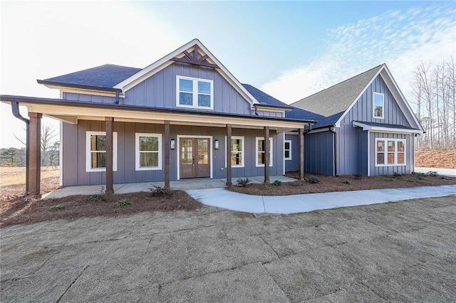 view of front of home featuring covered porch, french doors, board and batten siding, and a shingled roof