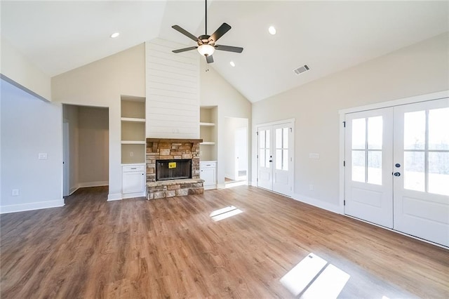 unfurnished living room featuring light wood-style floors, french doors, visible vents, and a fireplace