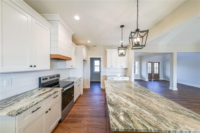 kitchen with a wealth of natural light, electric stove, dark wood-style floors, a kitchen island, and backsplash