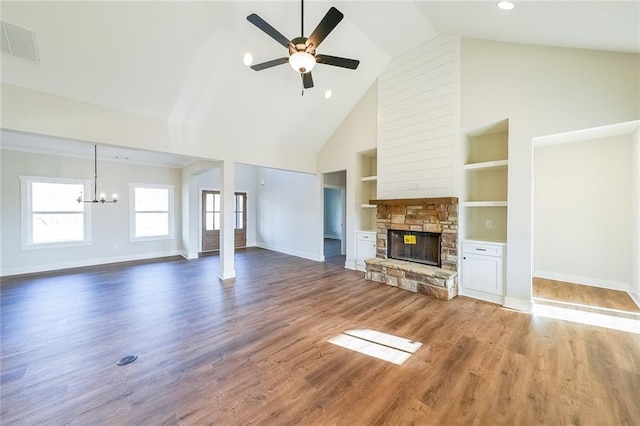 unfurnished living room featuring built in features, a fireplace, wood finished floors, baseboards, and ceiling fan with notable chandelier