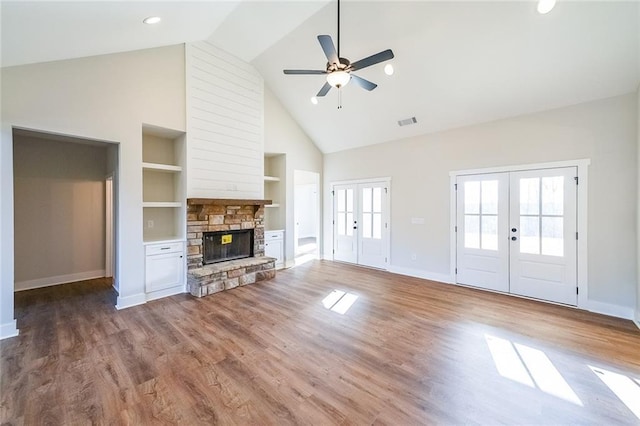 unfurnished living room with a fireplace, visible vents, wood finished floors, and french doors