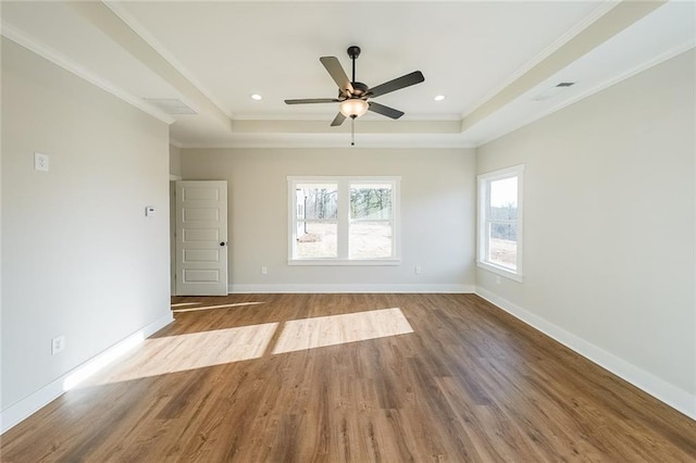 empty room featuring ornamental molding, a tray ceiling, and wood finished floors