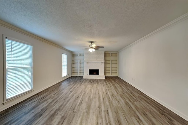 unfurnished living room featuring wood-type flooring, ceiling fan, built in features, a fireplace, and a textured ceiling