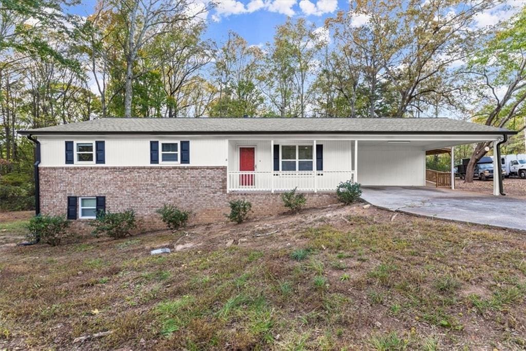 ranch-style house featuring covered porch and a carport