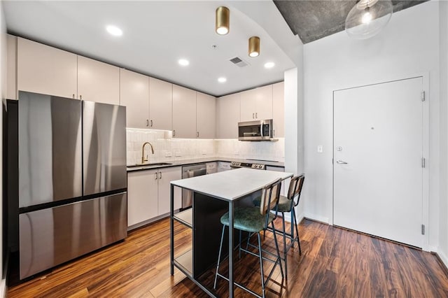 kitchen with dark wood-type flooring, stainless steel appliances, a kitchen breakfast bar, and sink