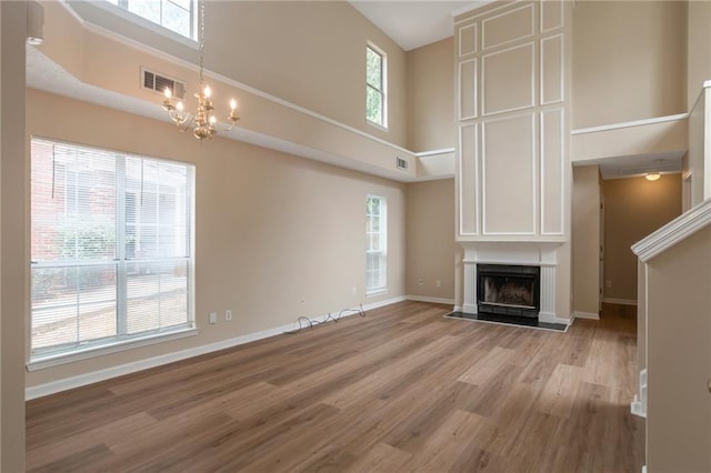 3984 Oak Glenn Dr, Duluth, GA 30096 - unfurnished living room with a high ceiling, a chandelier, baseboards, light wood-style floors, and a fireplace