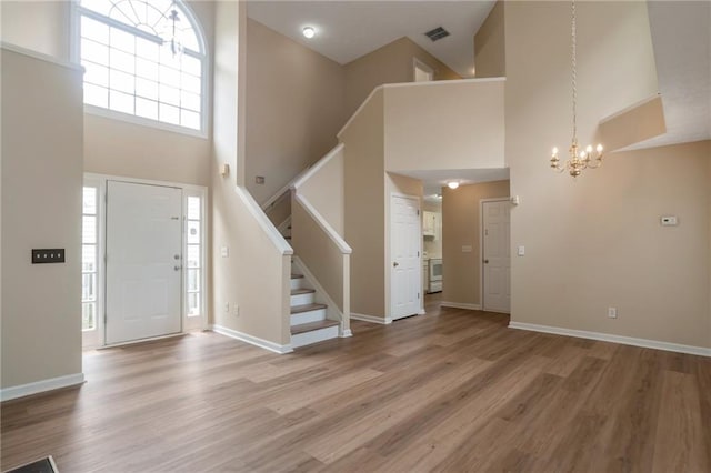 3984 Oak Glenn Dr, Duluth, GA 30096 - entryway featuring a towering ceiling, a chandelier, stairway, light wood finished floors, and baseboards