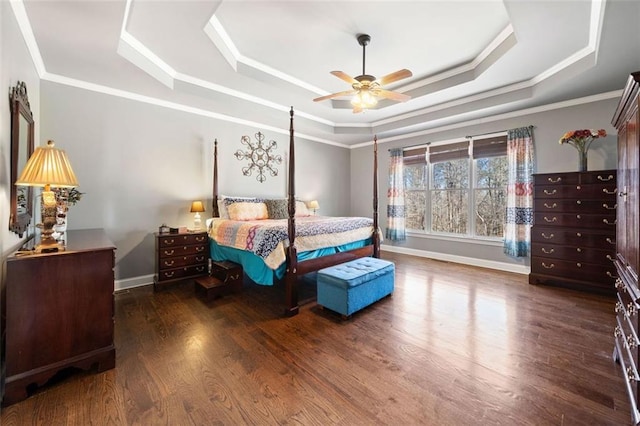 bedroom featuring ceiling fan, dark wood-type flooring, ornamental molding, and a tray ceiling