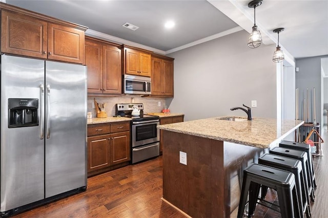 kitchen featuring stainless steel appliances, sink, hanging light fixtures, a kitchen island with sink, and crown molding