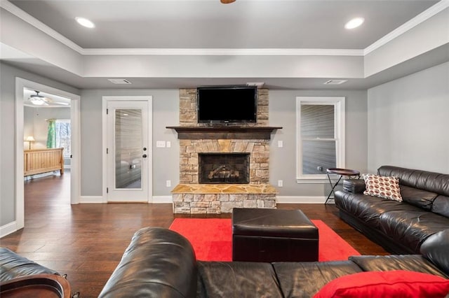 living room featuring ceiling fan, dark wood-type flooring, crown molding, and a fireplace