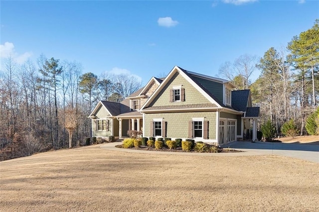 view of front of home featuring a porch, a front lawn, and a garage