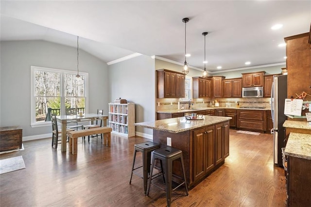 kitchen with a kitchen island, stainless steel appliances, vaulted ceiling, and decorative light fixtures