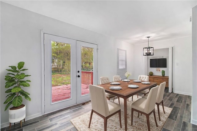 dining room featuring an inviting chandelier, french doors, baseboards, and wood finish floors