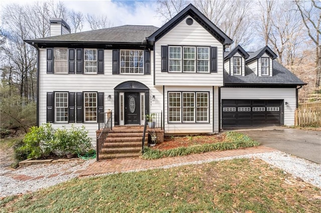 view of front of home with aphalt driveway, a shingled roof, a chimney, and a garage