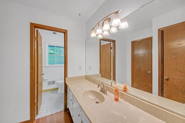 4856 Rock Haven Dr, Lilburn, GA 30047 - bathroom with wood finished floors, toilet, vanity, baseboards, and a chandelier