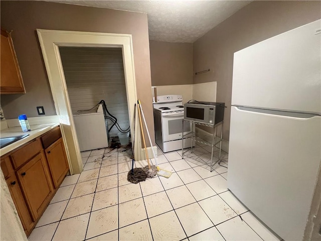 1165 Oak St SW, Atlanta, GA 30310 - kitchen with white appliances, brown cabinets, light countertops, washer / clothes dryer, and light tile patterned floors
