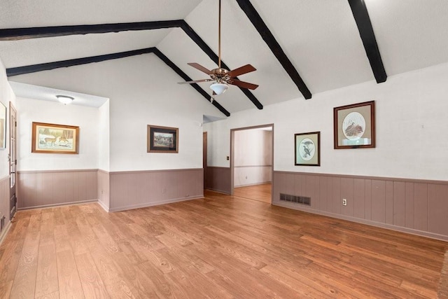 unfurnished living room with lofted ceiling with beams, ceiling fan, and light wood-type flooring