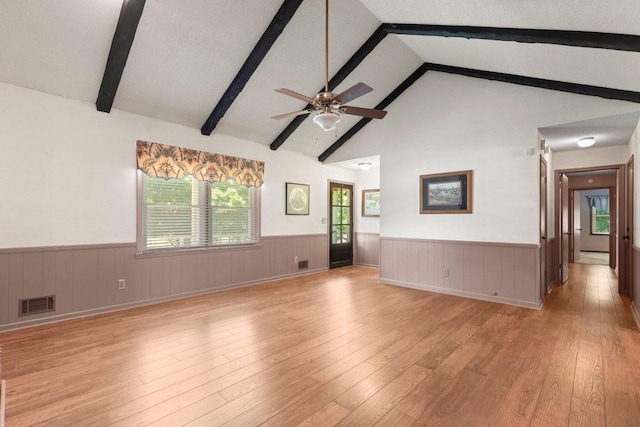 unfurnished living room featuring ceiling fan, a textured ceiling, light hardwood / wood-style flooring, and vaulted ceiling with beams