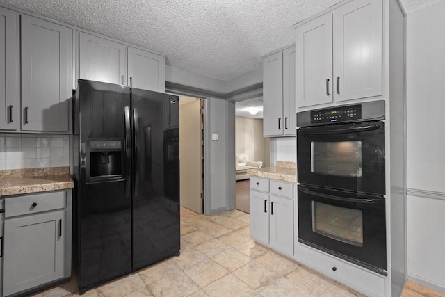 kitchen featuring gray cabinetry, tasteful backsplash, light stone counters, a textured ceiling, and black appliances