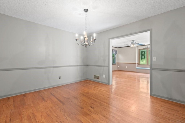 spare room featuring a notable chandelier, a textured ceiling, and light hardwood / wood-style floors