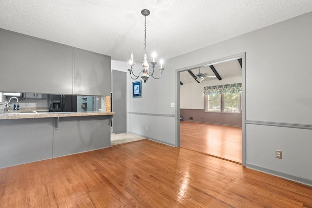 kitchen featuring a kitchen bar, sink, light wood-type flooring, kitchen peninsula, and ceiling fan with notable chandelier