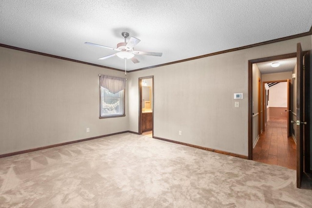 spare room featuring ceiling fan, ornamental molding, light colored carpet, and a textured ceiling