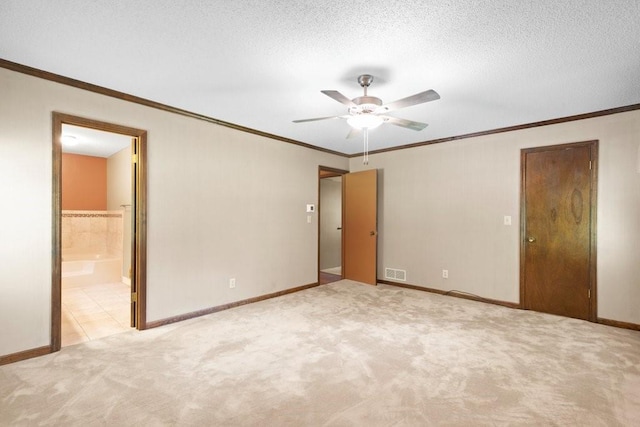 unfurnished bedroom featuring ensuite bath, ceiling fan, ornamental molding, a textured ceiling, and light carpet