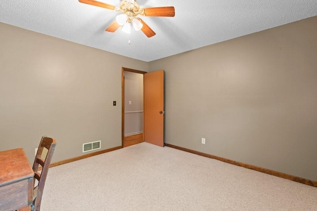 unfurnished office featuring ceiling fan, a textured ceiling, and carpet