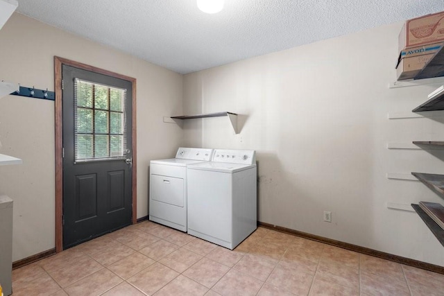 clothes washing area with light tile patterned floors, independent washer and dryer, and a textured ceiling