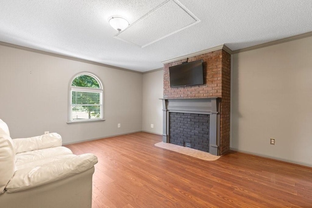 living room featuring ornamental molding, a brick fireplace, a textured ceiling, and light wood-type flooring