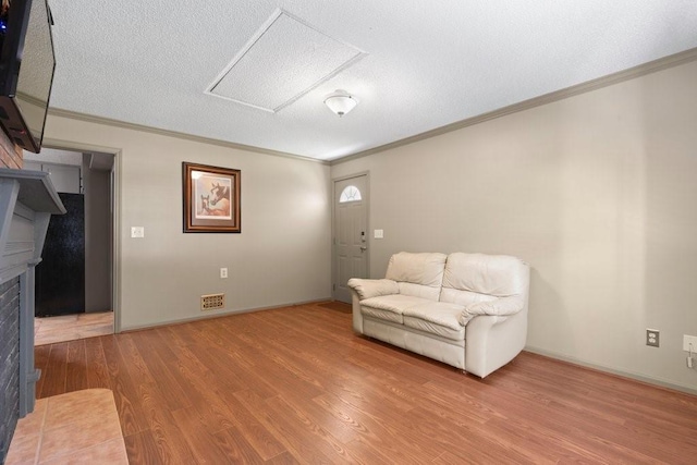 sitting room featuring ornamental molding, hardwood / wood-style floors, and a textured ceiling