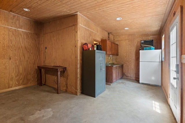 interior space featuring white refrigerator, wood ceiling, wooden walls, and sink