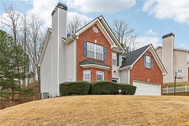 traditional-style house with a garage, a chimney, cooling unit, a front lawn, and brick siding