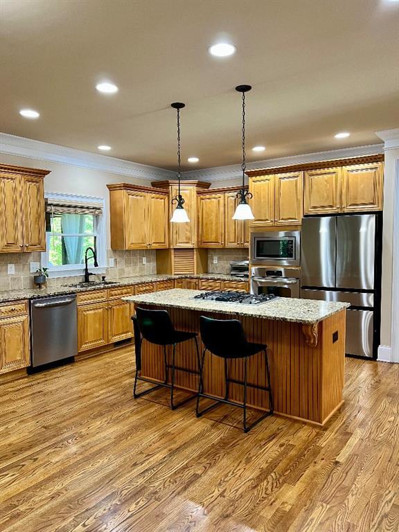 kitchen featuring a center island, sink, stainless steel appliances, crown molding, and decorative backsplash