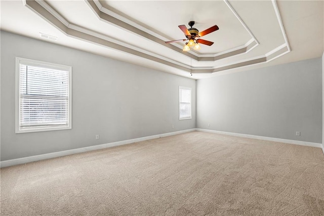 carpeted spare room featuring crown molding, a raised ceiling, and ceiling fan