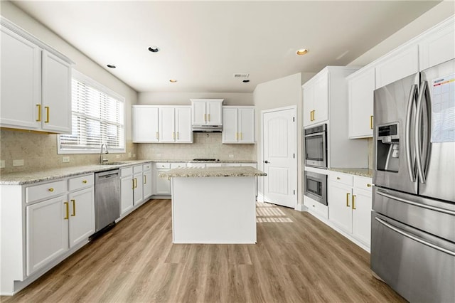 kitchen featuring light stone counters, stainless steel appliances, a kitchen island, and white cabinets