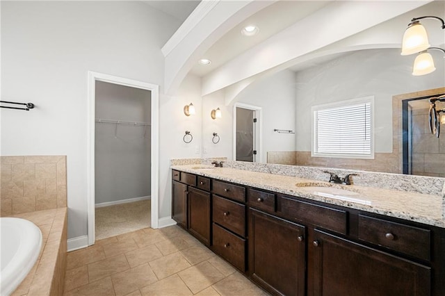 bathroom with vanity, tile patterned flooring, and tiled tub