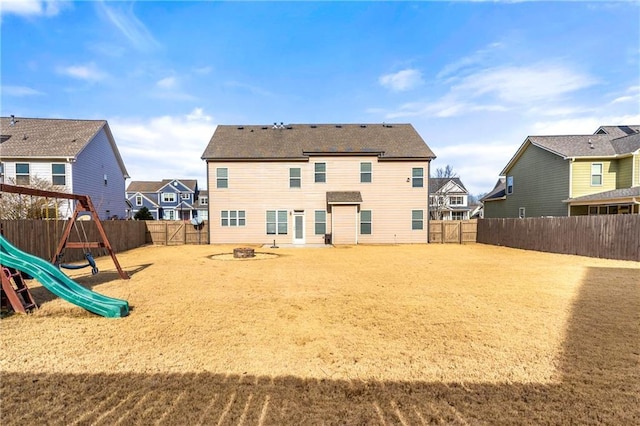 rear view of property with a playground and an outdoor fire pit