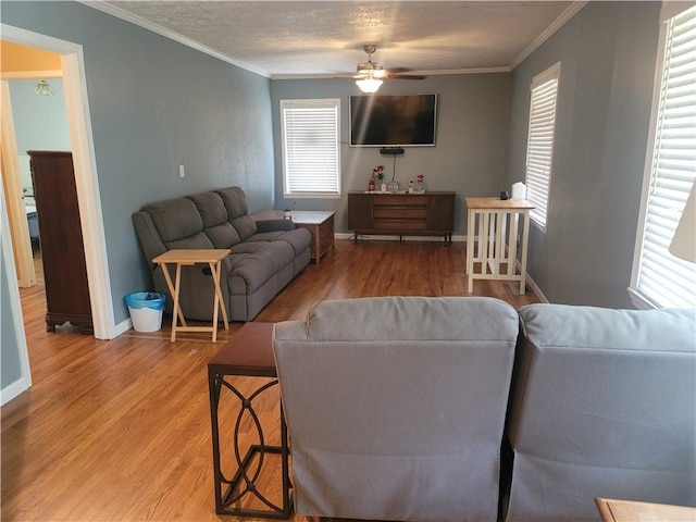 living room featuring crown molding, ceiling fan, wood-type flooring, and a textured ceiling