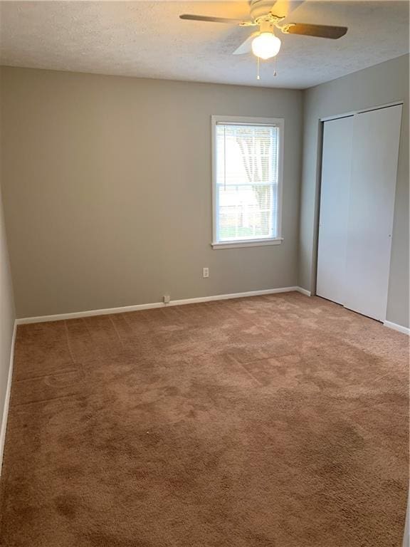 499 Oak Way, Lawrenceville, GA 30046 - unfurnished bedroom featuring light carpet, a closet, a textured ceiling, and a ceiling fan