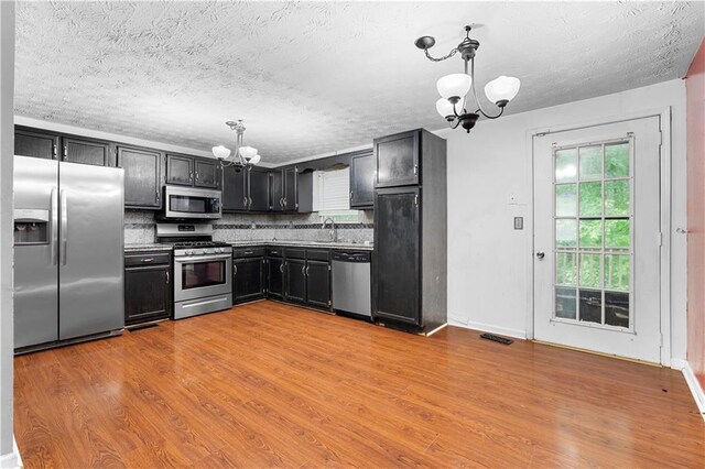 1822 Oriole Trl, Lithia Springs, GA 30122 - kitchen featuring appliances with stainless steel finishes, a chandelier, a sink, dark cabinets, and backsplash