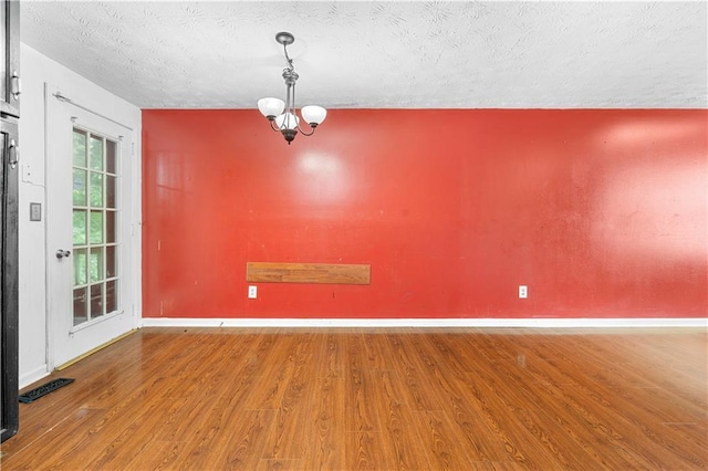 1822 Oriole Trl, Lithia Springs, GA 30122 - spare room featuring wood finished floors, a textured ceiling, baseboards, and a chandelier