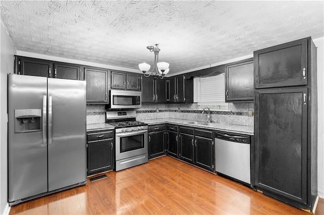 1822 Oriole Trl, Lithia Springs, GA 30122 - kitchen featuring appliances with stainless steel finishes, a sink, a chandelier, dark cabinets, and light wood-type flooring
