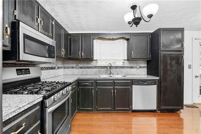 1822 Oriole Trl, Lithia Springs, GA 30122 - kitchen with stainless steel appliances, a sink, a textured ceiling, dark cabinetry, and light countertops