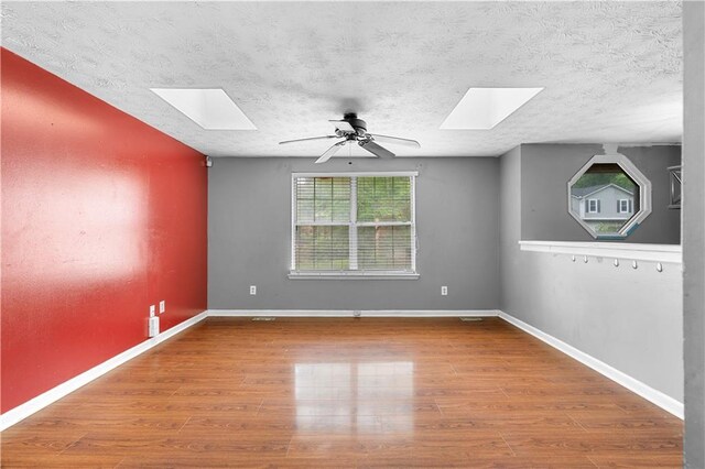 1822 Oriole Trl, Lithia Springs, GA 30122 - empty room featuring a skylight, a ceiling fan, wood finished floors, and a textured ceiling