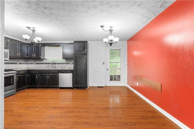 1822 Oriole Trl, Lithia Springs, GA 30122 - kitchen with appliances with stainless steel finishes, a chandelier, dark cabinetry, backsplash, and a textured ceiling