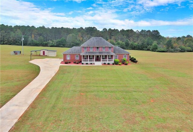 view of front of home with covered porch, a front yard, and an outbuilding