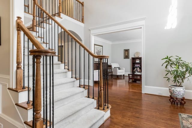 stairway featuring ornamental molding, baseboards, and wood finished floors